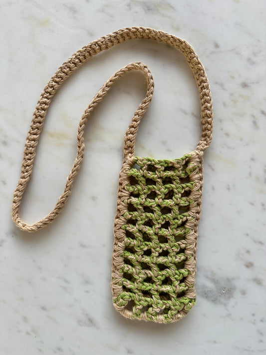 Shows the crocheted in 'call me' phonebag in beige and neon green with an open mesh pattern. Made by The Woollers