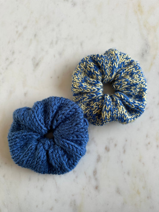The image shows two knitted scrunchies in different colorways. One is cobalt blue, the other has a mix of a soft yellow and blue. Made by The Woollers