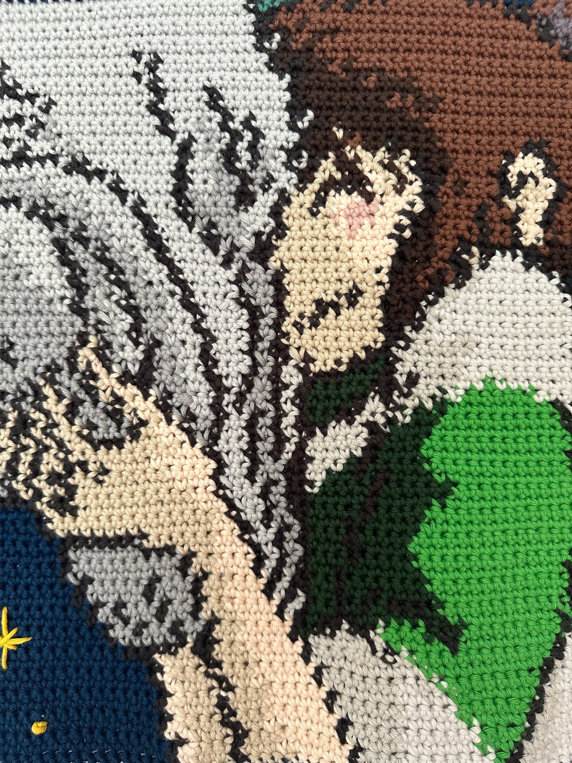 Shows a close up of our crocheted tapestry of a still out of the movie 'Spirited Away', in which Haku and Chihiro are embracing. Made by The Woollers 