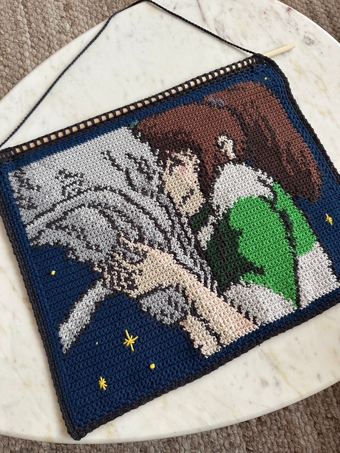 Shows our crocheted tapestry of a still out of the movie 'Spirited Away', in which Haku and Chihiro are embracing. Made by The Woollers 