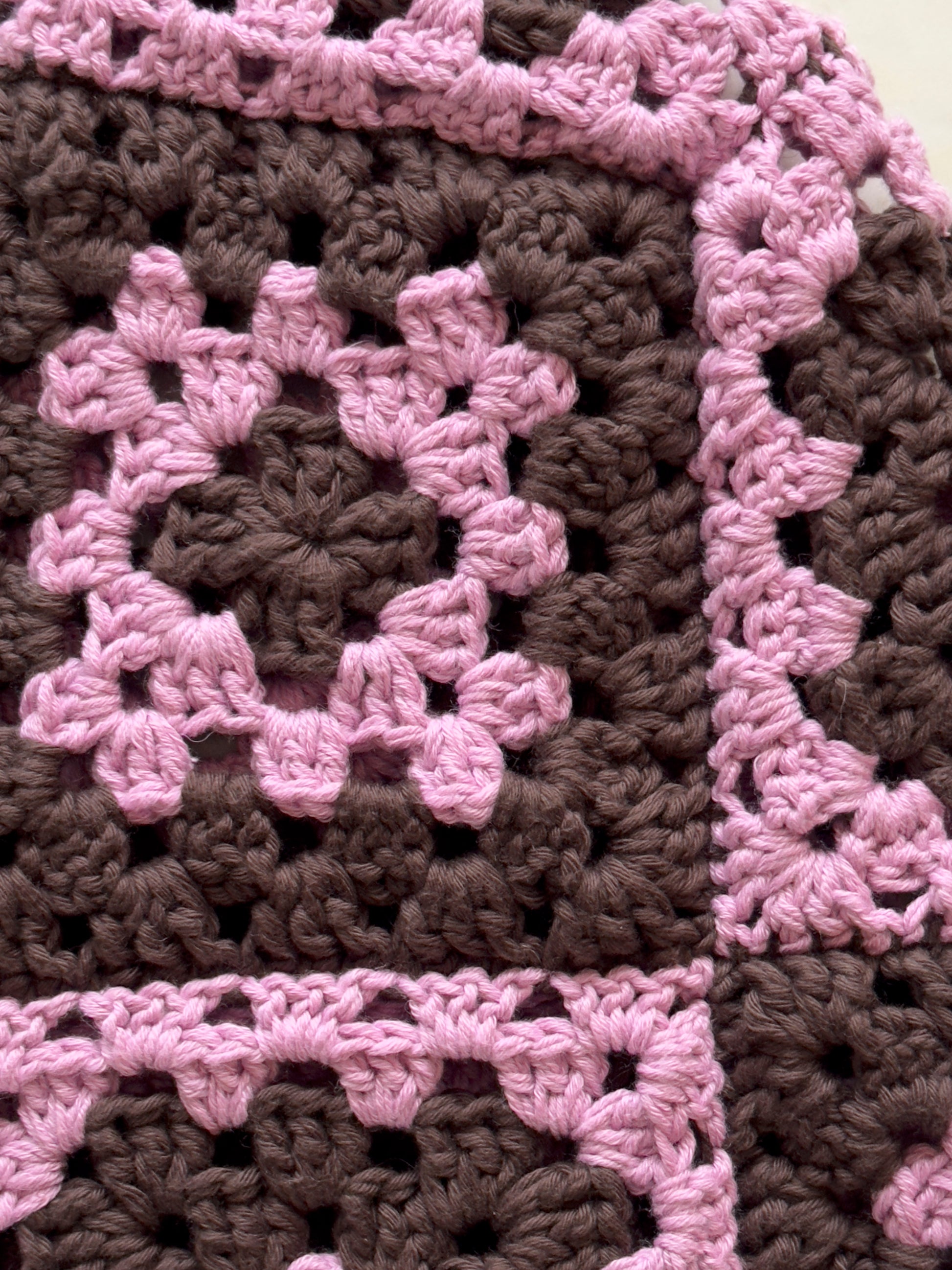 Shows a close up of the crocheted umi balaclava which is made of pink and brown granny squares. Made by The Woollers