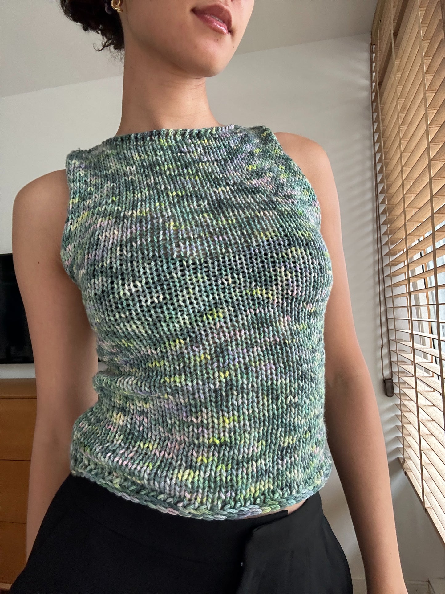 Shows a model wearing our knitted multi-colored 'iris' tank top in shades of green, blue and pink. Made by The Woollers