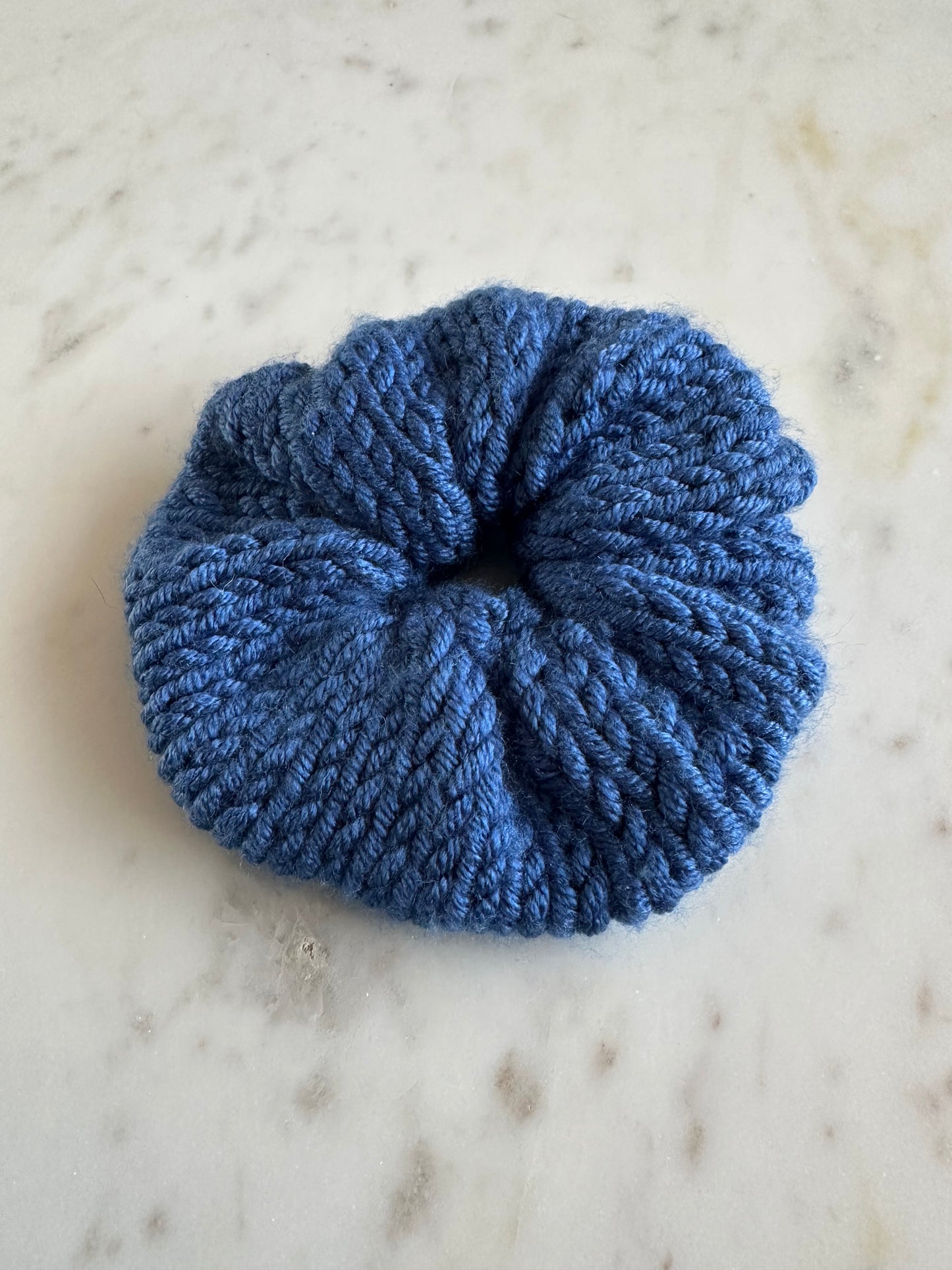 The image shows a knitted cobalt blue scrunchie. Made by The Woollers