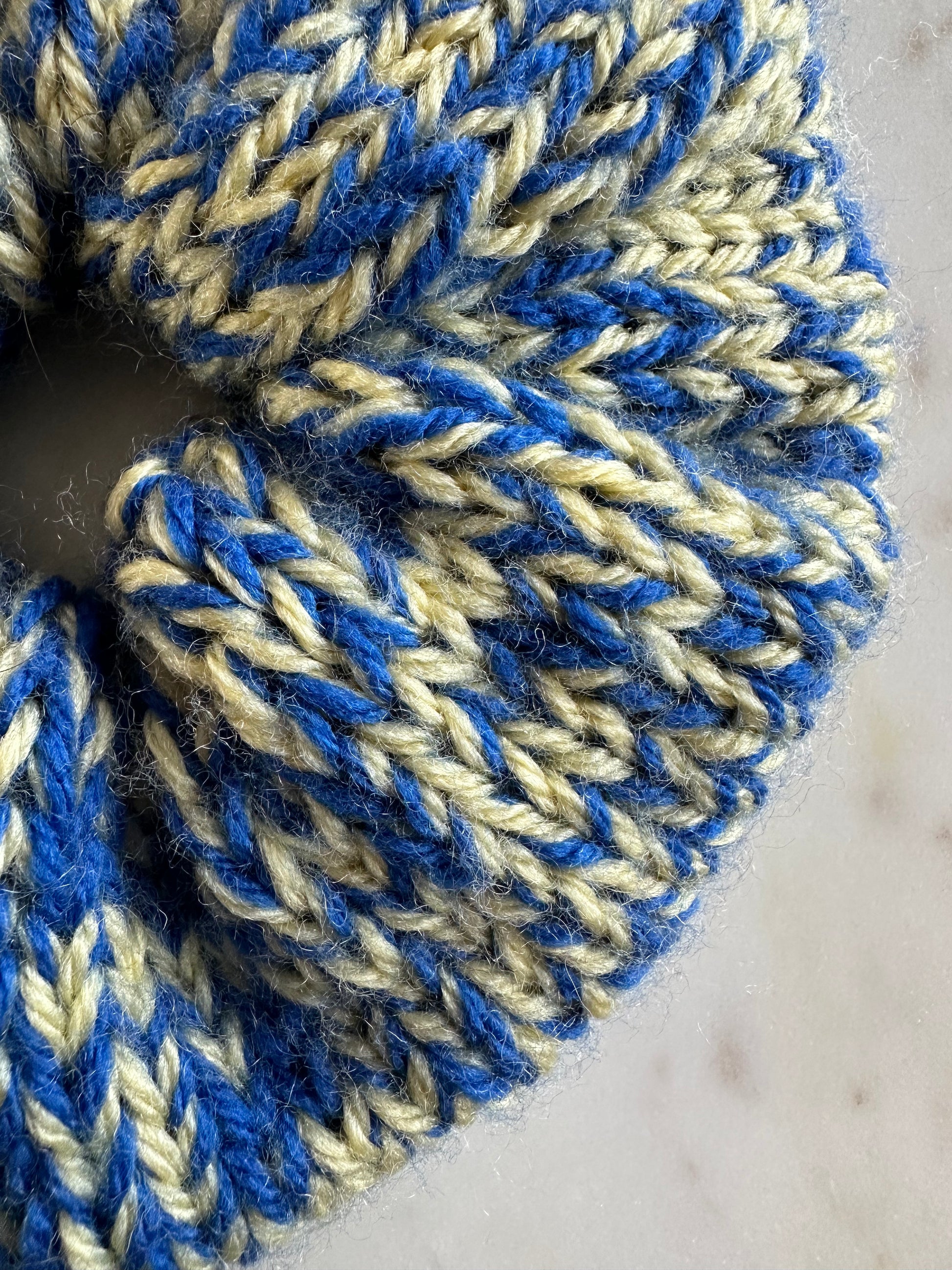 Shows a close up of the knitted pattern of our 'TOBY' scrunchie. It has a mix of soft yellow and blue. Made by The Woollers